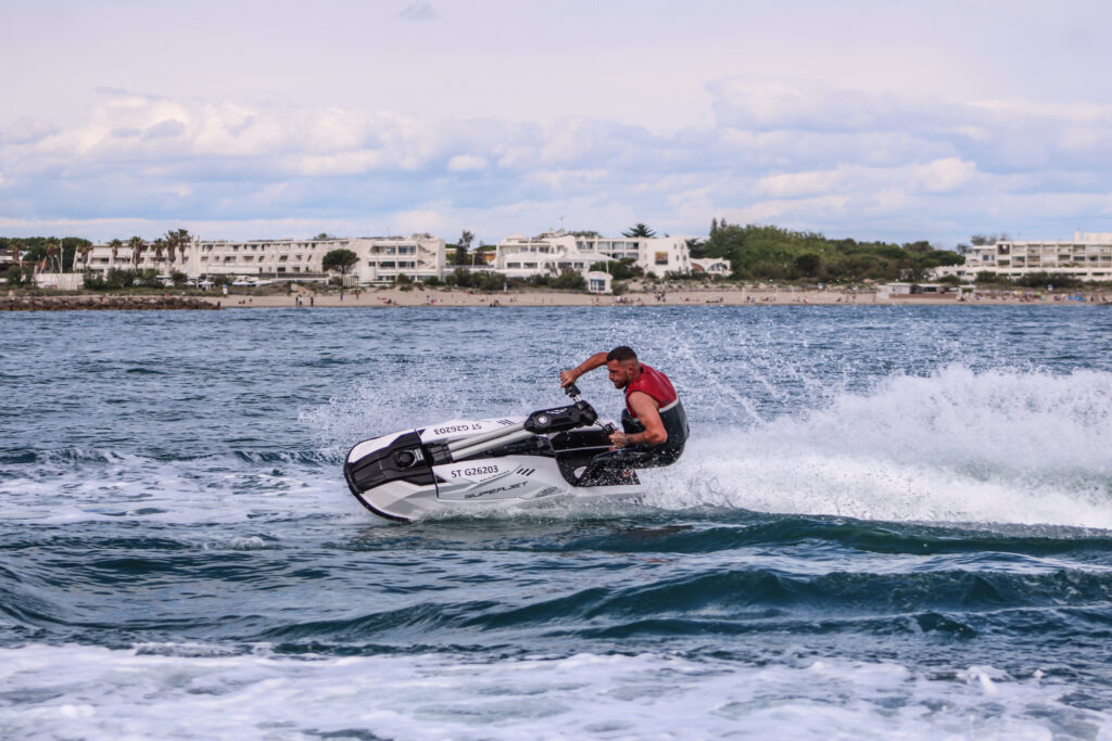 Homme faisant du jet ski sur l’eau avec vue sur le littoral. Formation BPJEPS Motonautisme